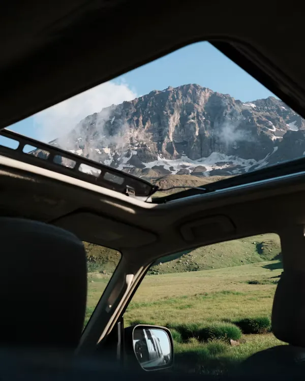 Sommet de montagne vu par le toit ouvrant d'une voiture