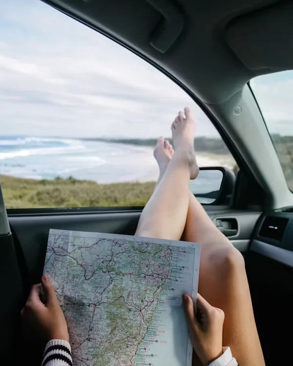 Carte routière dépliée dans une voiture face à l'océan